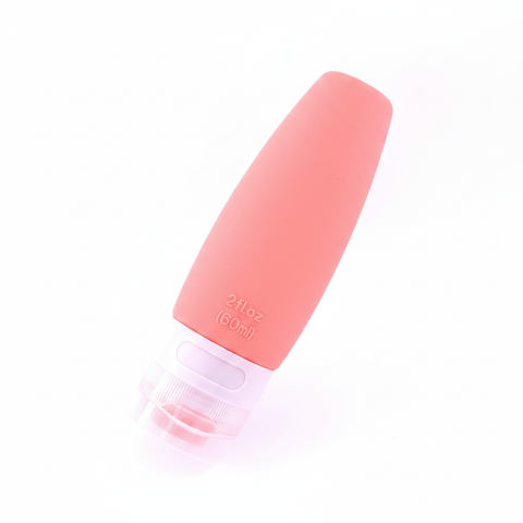 Coral pink silicone travel bottle 60ml at 45 degree angle showing smooth body and clear bottom screw cap on white background