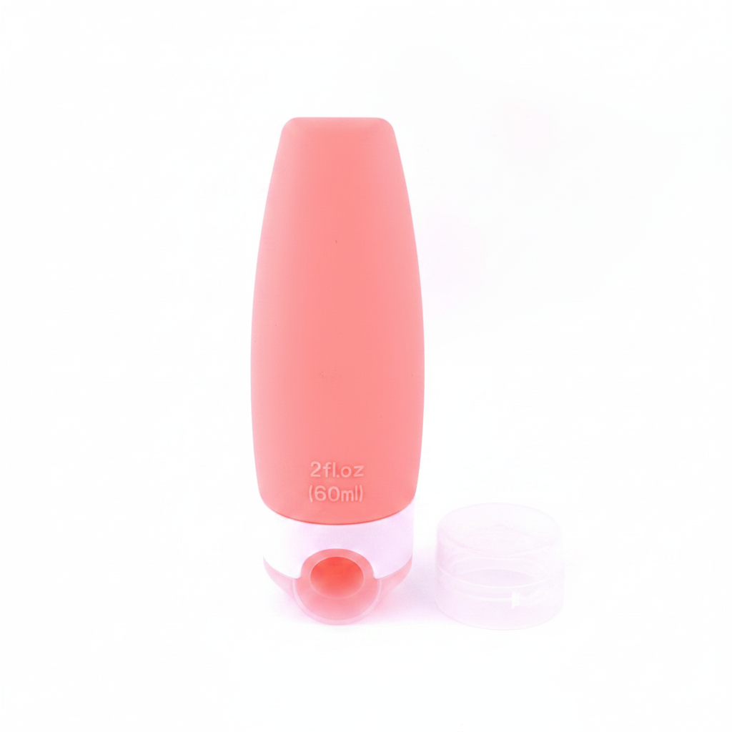 Coral pink silicone travel bottle with clear bottom cap removed showing wide mouth refill opening on white background