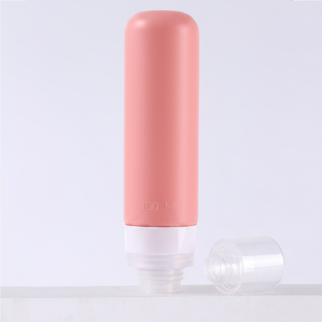 Dusty rose pink silicone travel bottle with clear bottom cap removed showing wide mouth refill opening on white background