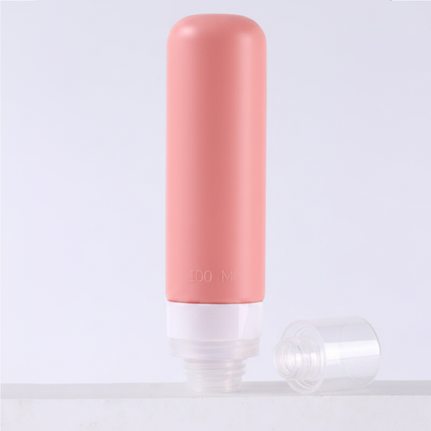 Dusty rose pink silicone travel bottle with clear bottom cap removed showing wide mouth refill opening on white background