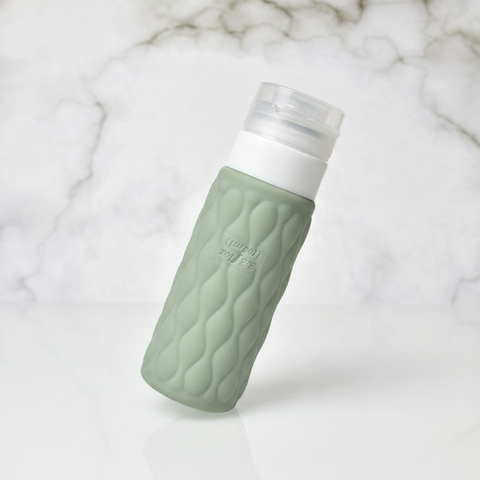 Sage green wave textured silicone travel bottle at 45 degree angle showing geometric texture and white leakproof cap on white background