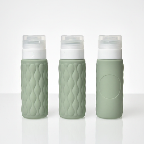 Three sage green diamond textured silicone travel bottles showing front side and back angles on white background